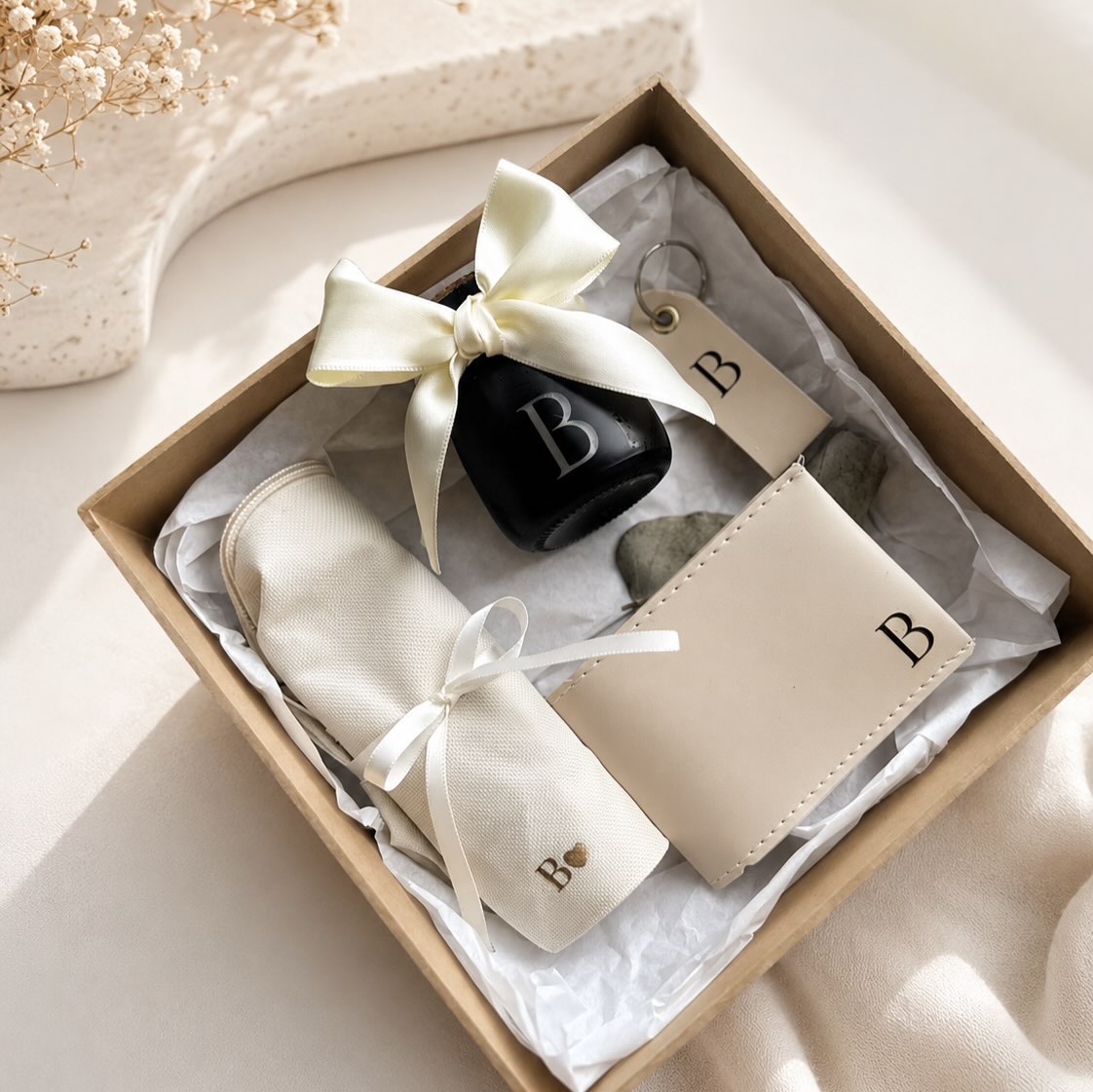 Kit personalizado em caixa kraft com carteira, chaveiro e frasco com inicial 'B'.
